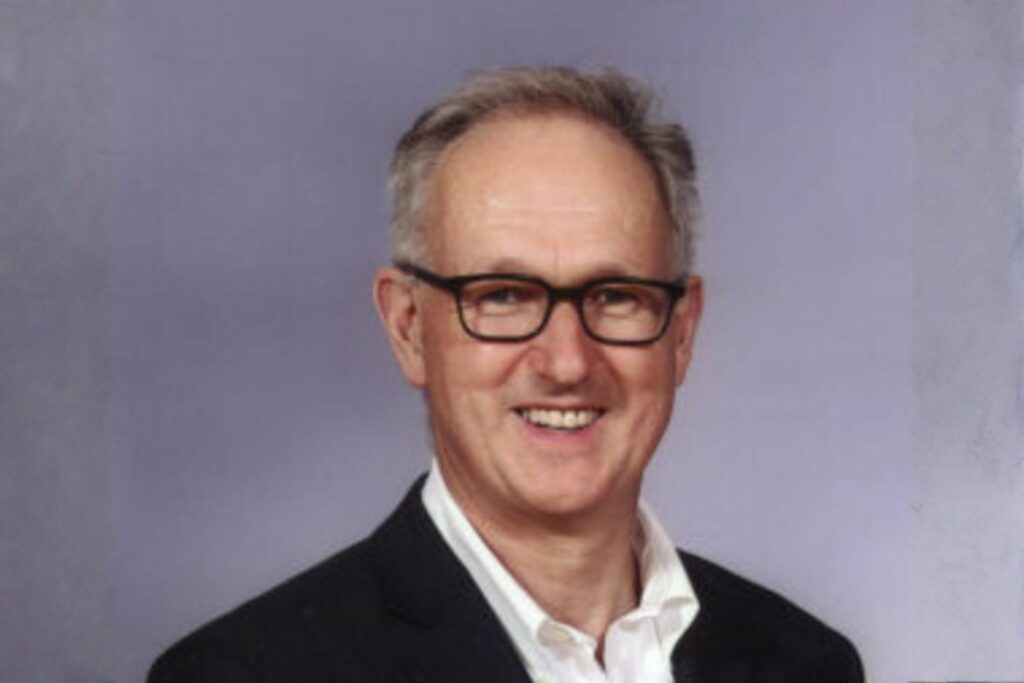 Julian Dobson of Julian Dobson Solicitors is pictured smiling, wearing glasses, and he is also wearing a black suit with a white shirt.